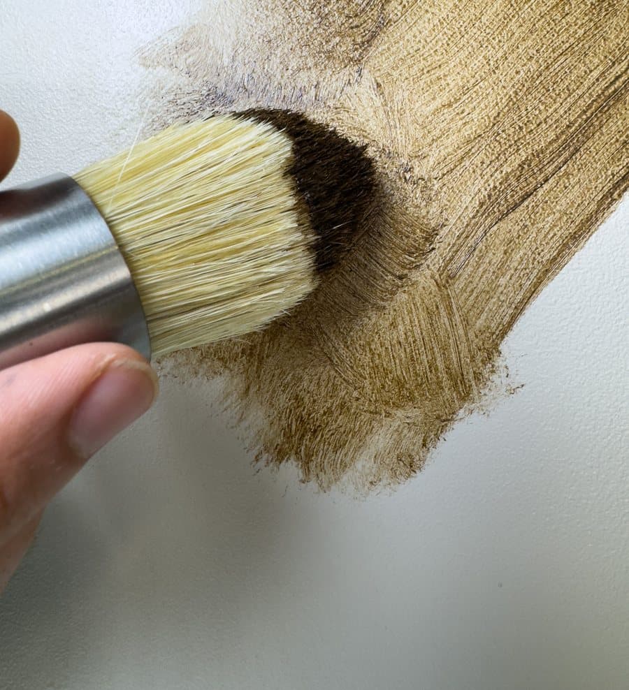 A round chalk paint brush applying paint to a surface