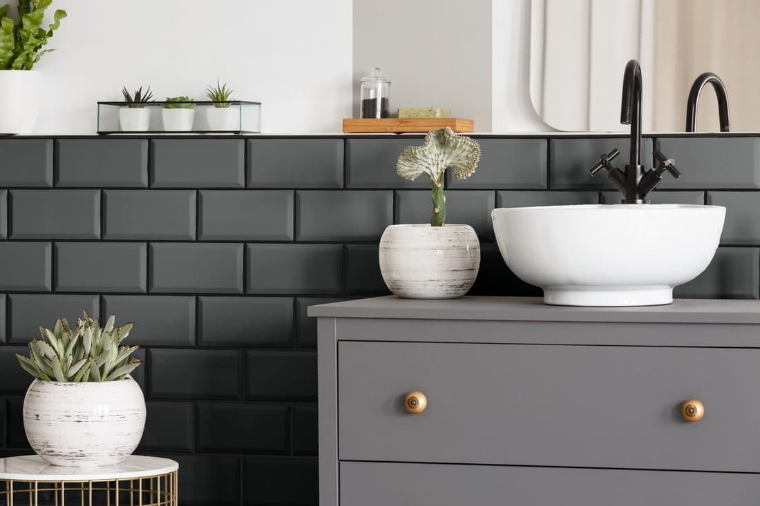 A moody bathroom with deep charcoal tile and dark fixtures