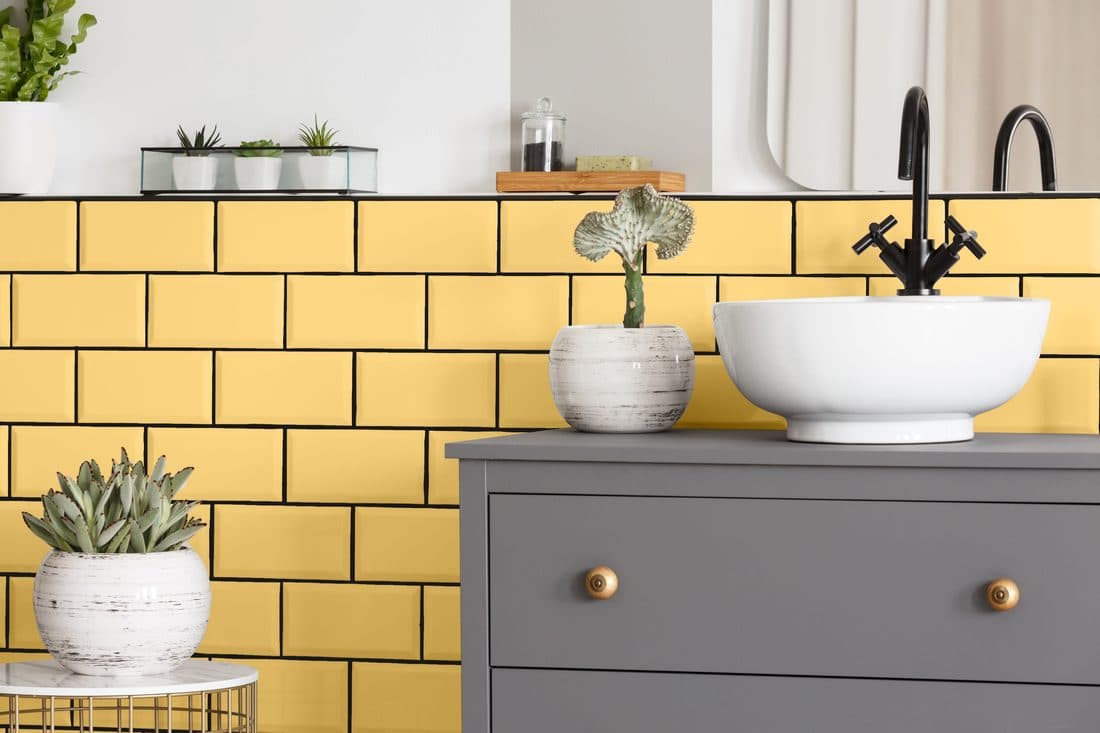 A bathroom with a painted yellow tile backsplash